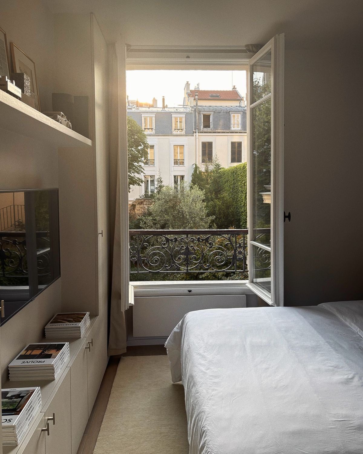 Chambre lumineuse avec fenêtre ouverte sur un balcon parisien